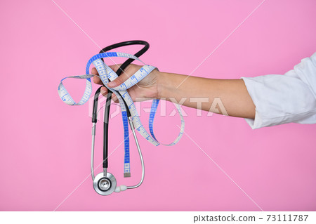 Doctor hand holding a measuring tape and a stethoscope 73111787