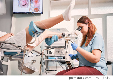 Gynecologist examining female patient with colposcope. Gynecologist examining female patient with colposcope. 73111819