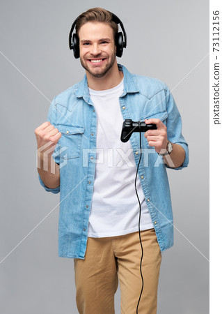 young man in casual jeans shirt holding joystick or gamepad playing game 73112156