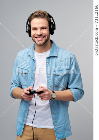 young man in casual jeans shirt holding joystick or gamepad playing game young man in casual jeans shirt holding joystick or gamepad playing game 73112166