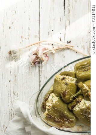 Pepper stuffed with white cheese, herbs, garlic. Glass dish prepared with seasonal local vegetables. White wood background. Soft focus Pepper stuffed with white cheese, herbs, garlic. Glass dish prepared with seasonal local vegetables. White wood background. Soft focus 73114812