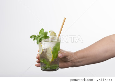 Select focus of a tempting mojito cocktail being held by a male hand on a light background 73116853