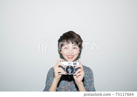 Young woman holding a film camera Young woman holding a film camera 73117884