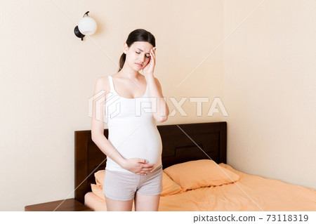 Young pretty pregnant woman suffering from headache at home in bed 73118319