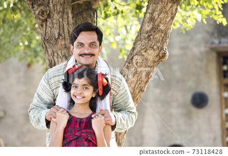 Rural Indian father with daughter looking at camera Rural Indian father with daughter looking at camera 73118428