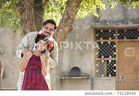 Rural Indian father with daughter looking at camera Rural Indian father with daughter looking at camera 73118430
