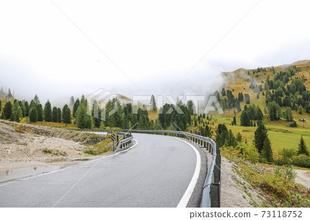 Slippery wet road high in the mountains. Misty morning in the Dolomites. Italy. Selective focus. Slippery wet road high in the mountains. Misty morning in the Dolomites. Italy. Selective focus. 73118752