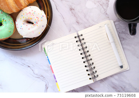 high angle view of open notepad, tea and donuts on tiles background high angle view of open notepad, tea and donuts on tiles background 73119608