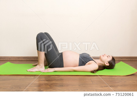 Pregnant woman meditating while sitting in yoga position. Meditating on maternity Pregnancy Yoga and Fitness concept at coronavirus time 73120061