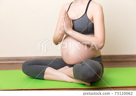 Pregnant woman meditating while sitting in yoga position. Meditating on maternity Pregnancy Yoga and Fitness concept at coronavirus time Pregnant woman meditating while sitting in yoga position. Meditating on maternity Pregnancy Yoga and Fitness concept at coronavirus time 73120062