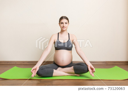 Beautiful pregnant woman doing yoga at home. Pregnancy Yoga and Fitness concept at coronavirus time Beautiful pregnant woman doing yoga at home. Pregnancy Yoga and Fitness concept at coronavirus time 73120063