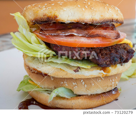 Young man eating a hamburger, Juicy and yummy hamburger Young man eating a hamburger, Juicy and yummy hamburger 73120279