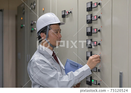 Middle man operating the switchboard in the factory facility 73120524