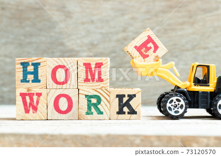 Bulldozer hold letter block E to complete word homework on wood background Bulldozer hold letter block E to complete word homework on wood background 73120570