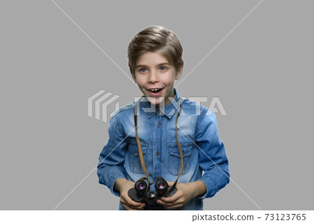 Excited preteen boy using binoculars. 73123765