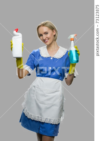 Woman maid holding two bottles of detergent. 73123875