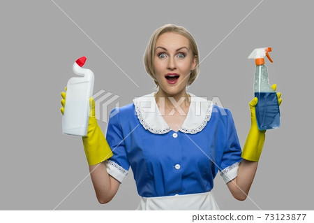 Excited housekeeping woman presenting cleaning supplies. 73123877