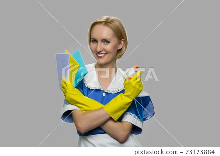 Pretty chambermaid holding cleaning spray and rags. 73123884