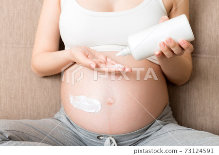 pregnant woman applying stretch mark cream to belly. pregnancy, people and maternity concept. pregnant apply anti-stretch mark cream on her belly pregnant woman applying stretch mark cream to belly. pregnancy, people and maternity concept. pregnant apply anti-stretch mark cream on her belly 73124591