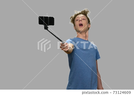 Teenage boy taking selfie using monopod. Teenage boy taking selfie using monopod. 73124609