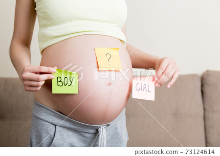 pregnant woman holding square multicolored stickers with question marks pregnant woman holding square multicolored stickers with question marks 73124614