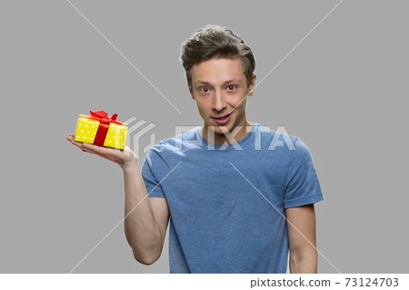 Caucasian teen boy holding small yellow gift box. 73124703