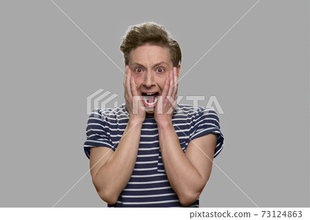 Shocked scared teen boy is screaming on gray background. 73124863