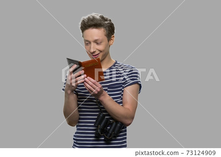 Happy teenage boy looking at his passport. Happy teenage boy looking at his passport. 73124909