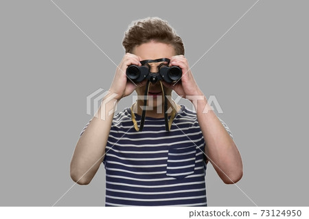 Caucasian teen boy looking through binoculars. Caucasian teen boy looking through binoculars. 73124950