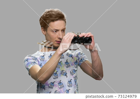 Boy using binoculars against gray background. 73124979