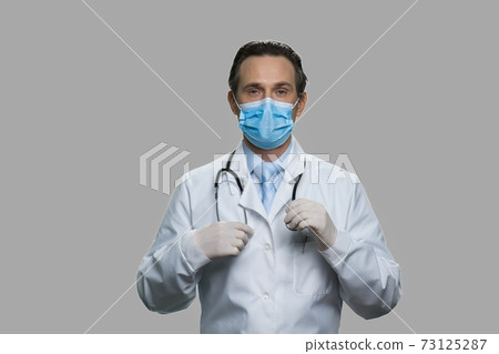 Male doctor with protective mask and sthesoscope looking at camera. Male doctor with protective mask and sthesoscope looking at camera. 73125287