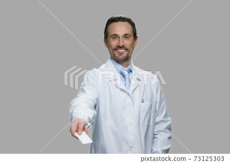 Successful male doctor offering business card. Successful male doctor offering business card. 73125303