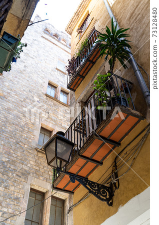 Yellow historic house with street light, flowers and balconies in Barcelona Yellow historic house with street light, flowers and balconies in Barcelona 73128480