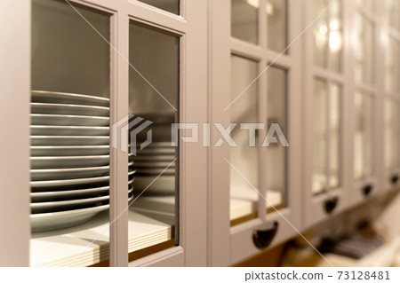 Row of plates in gray wooden cabinet with glass windows in traditional style Row of plates in gray wooden cabinet with glass windows in traditional style 73128481