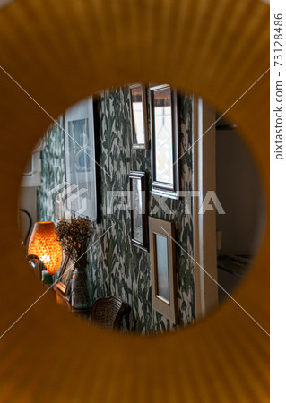 Reflection in mirror of lamp, framed pictures and wallpaper in floral pattern Reflection in mirror of lamp, framed pictures and wallpaper in floral pattern 73128486