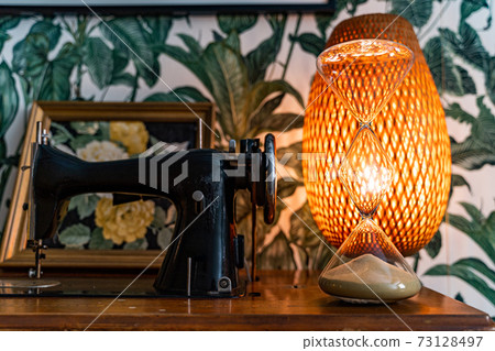Sewing machine, hourglass and lamp with wallpaper in floral tropical pattern 73128497