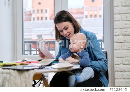 Young mother work with baby in her arms at home office 73128645