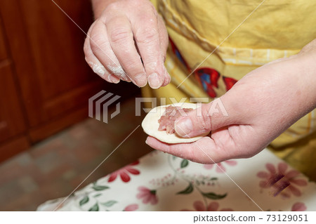 Hands hold a piece of raw dough and minced meat Hands hold a piece of raw dough and minced meat 73129051