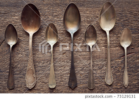 Seven empty alpacca vintage spoons on a wooden background, top view Seven empty alpacca vintage spoons on a wooden background, top view 73129131