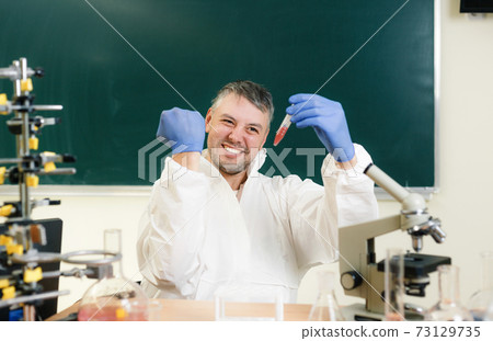The scientist chemist in the laboratory is satisfied with the result of his experiment. Real emotions. Close-up 73129735