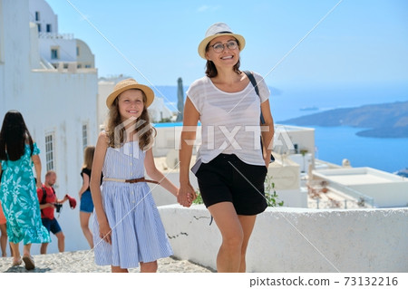 Happy tourists family mother and daughter kid walking on the Greek island of Santorini Happy tourists family mother and daughter kid walking on the Greek island of Santorini 73132216