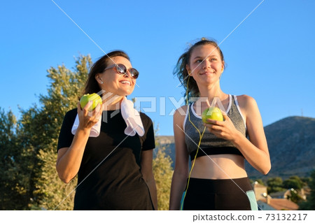 Athletic healthy family lifestyle, happy mother and teenage daughter eating apples Athletic healthy family lifestyle, happy mother and teenage daughter eating apples 73132217