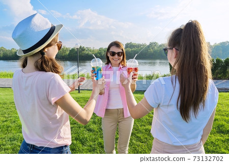 Portrait of happy mother and daughters teenagers 14 and 16 years old, with summer drinks Portrait of happy mother and daughters teenagers 14 and 16 years old, with summer drinks 73132702