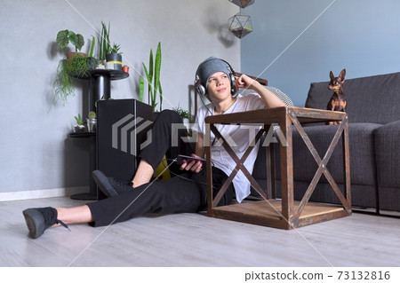 Teenage boy hipster in headphones with smartphone listening to music Teenage boy hipster in headphones with smartphone listening to music 73132816