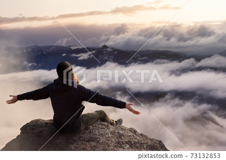 Adventurous Man with Open Hands is taking in the momen on top of a mountain. Adventurous Man with Open Hands is taking in the momen on top of a mountain. 73132853