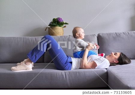 Happy mother with toddler son at home. Laughing woman playing with baby 73133605