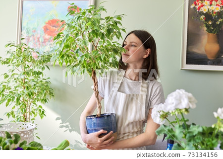 Portrait of beautiful smiling teenage girl with potted plants. Portrait of beautiful smiling teenage girl with potted plants. 73134156