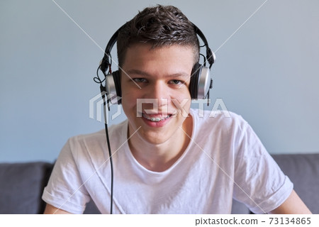 Portrait of student boy teenager in headphones looking at webcam, videocall 73134865