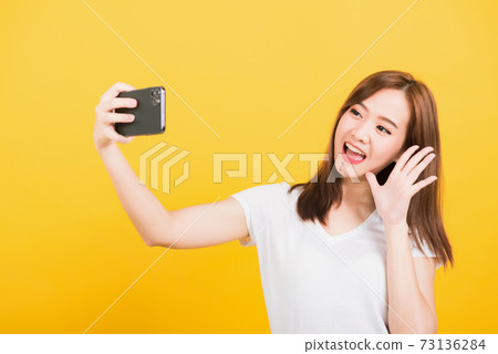 woman teen smiling standing wear t-shirt making selfie photo, video call on smartphone woman teen smiling standing wear t-shirt making selfie photo, video call on smartphone 73136284