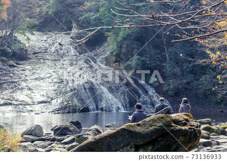 [Tourists enjoying the autumn leaves of Awamata Waterfall] 73136933